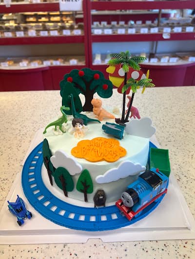 Two-tier cake decorated with a train track and trees