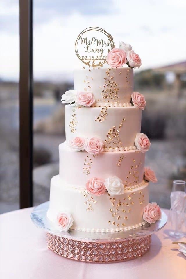 Pink tiered celebration cake with roses and a topper